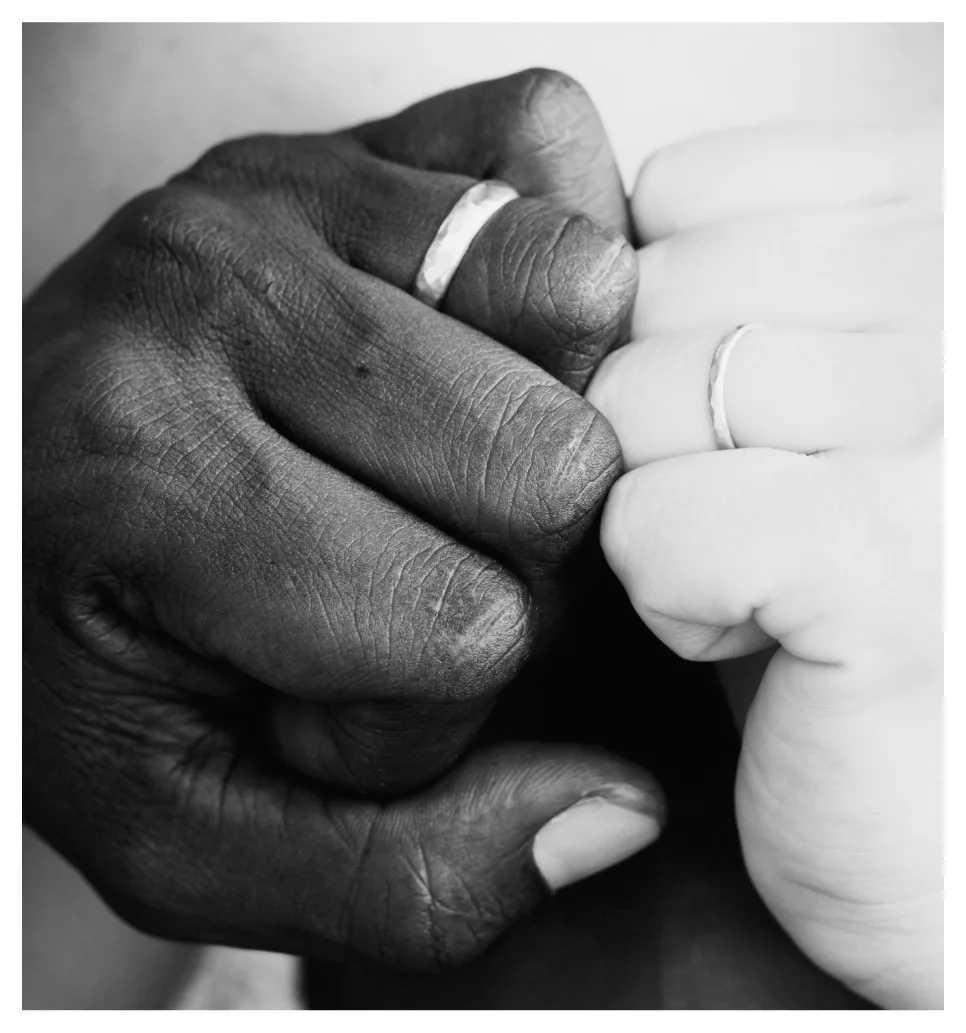 Image-16.png A black and white close-up of two clasped hands, each wearing a simple wedding band.
